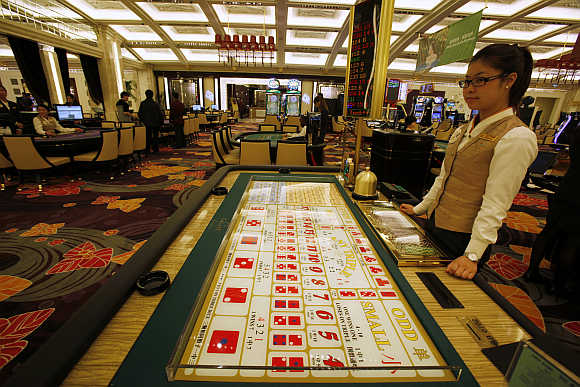 A croupier stands in front of a gaming table inside a casino in Macau.