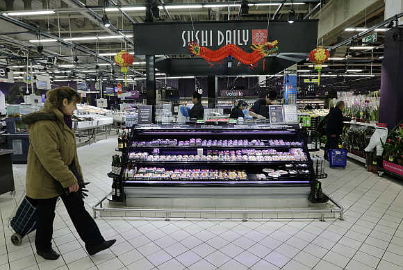 A customer walks past Sushi daily bar foods section at Carrefour's Bercy hypermarket in Charenton, a Paris suburb.