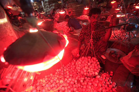 A worker weighs onions in a wholesale market at Kawranbazar in Dhaka, Bangladesh.