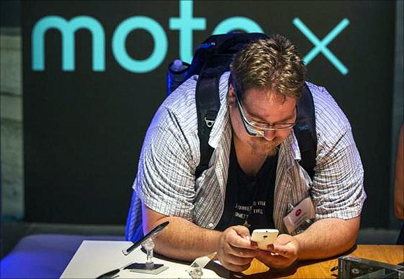A man using Google Glass examines one of Motorola's new Moto X phones.