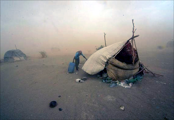 Gold mine workers walk to their shelter during a sandstorm in Al-Ibedia locality at River Nile State.