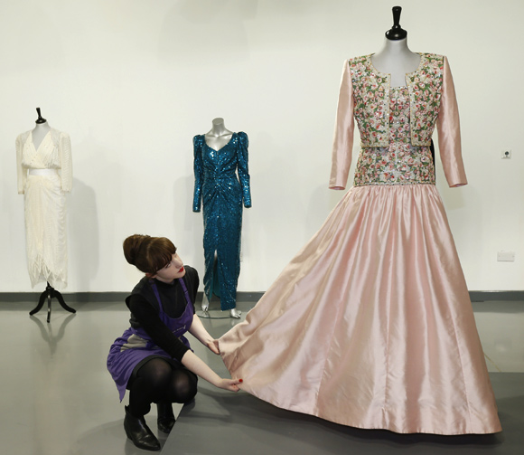 House assistant Lucy Bishop poses with a Catherine Walker Mughal-inspired pink slubbed silk evening gown and bolero worn by Diana, Princess of Wales, at Kerry Taylor Auctions in London.