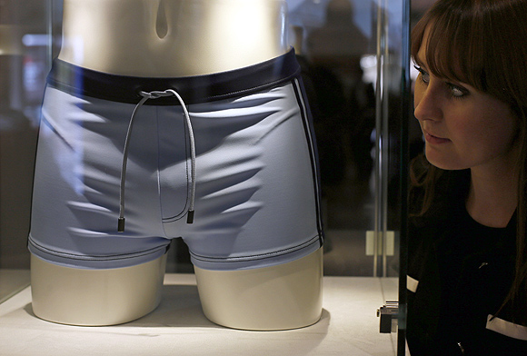 A employee poses next to a pair of swimming trunks, worn by Daniel Craig in the film Casino Royal, during a media preview of 50 Years of James Bond - the Auction, at Christie's in London.