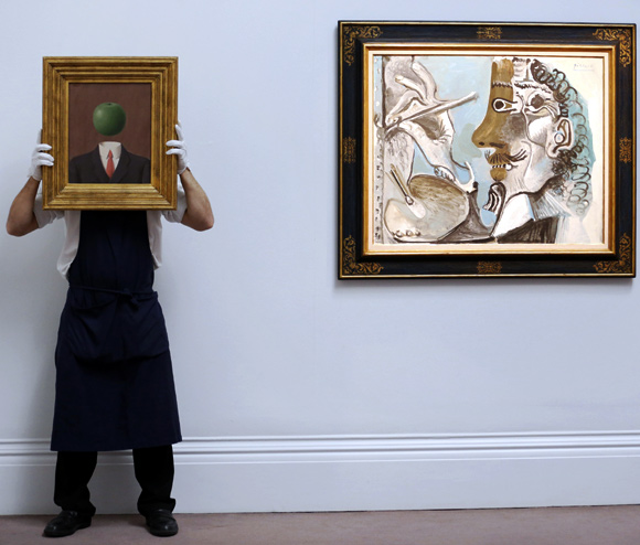 A Sotheby's employee poses with Rene Magritte's artwork L'idee (L) alongside Pablo Picasso's picture Le Peitnre at Sotheby's auction house in London.