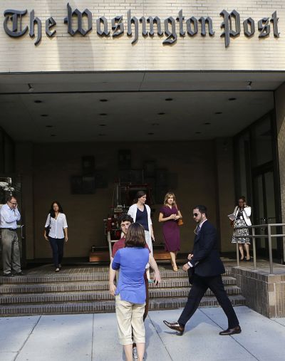 People walk by the entrance of the Washington Post headquarters in Washington.