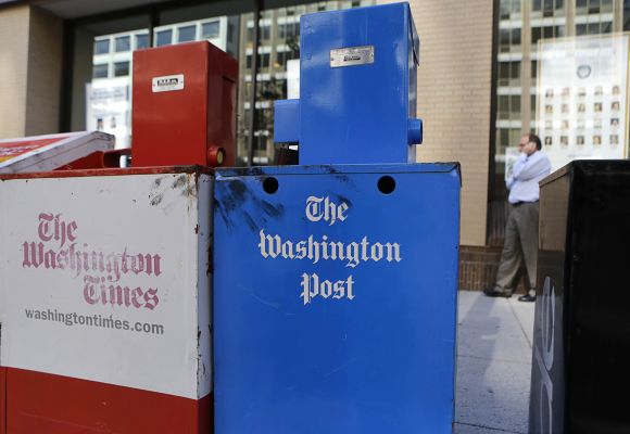 Washington Post (R) and Washington Times newspaper boxes are pictured outside the entrance to the Washington Post headquarters in Washington
