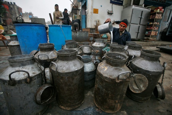 A milkman pours milk into a container to deliver to shops in Noida, Uttar Pradesh.