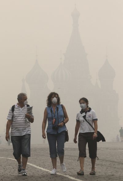 Tourists, wearing masks to protect themselves from heavy smog, walk along Red Square in central Moscow.