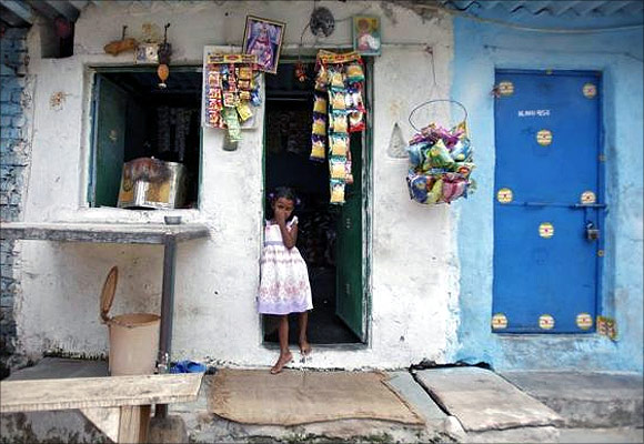 A girl stands at the door of a grocery shop at a slum in New Delhi.
