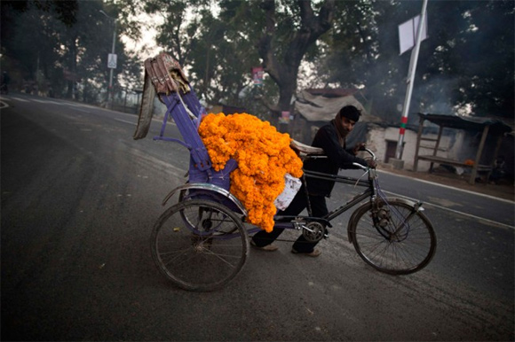A man transports garlands of marigold flowers along the banks of the Ganges river ahead of Kumbh Mela in Allahabad. 
