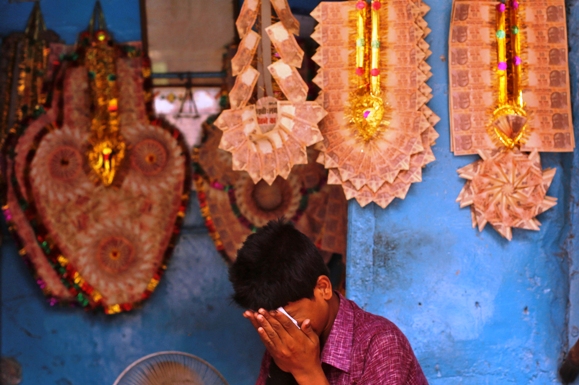 A vendor wipes his face at a shop selling garlands made of Indian currency notes in the old quarters of Delhi.