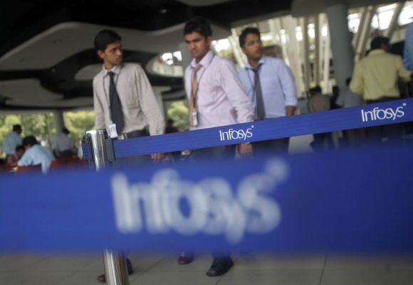 Employees of Indian software company Infosys walk past Infosys logos at their campus in the Electronic City area in Bangalore.