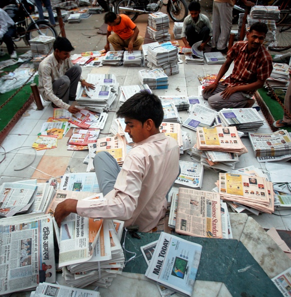 Distributors sort through newspapers before selling them during early hours in Noida.