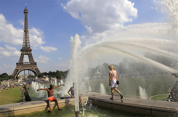 People cool off in a fountain at the Trocadero Square in front of the Eiffel Tower on a warm summer afternoon in Paris.