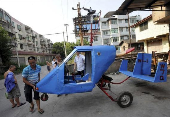 Wen Jiaquan (2nd L), 54-year-old motorcycle mechanic, moves his self-made helicopter in Qingping township of Chongqing municipality.