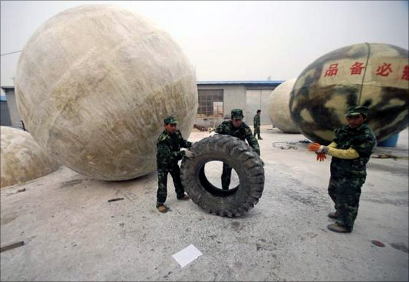 Workers move a tyre near spherical pods named Noah's Ark, designed by Chinese inventor Liu Qiyuan in Xianghe, Hebei province.