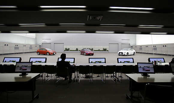 Toyota's Managing Officer Tokuo Fukuichi looks at Auris, left, a clay model of concept vehicle NS4, centre, and luxury brand Lexus, left, inside a decision room at the company's design centre building in Toyota, central Japan.