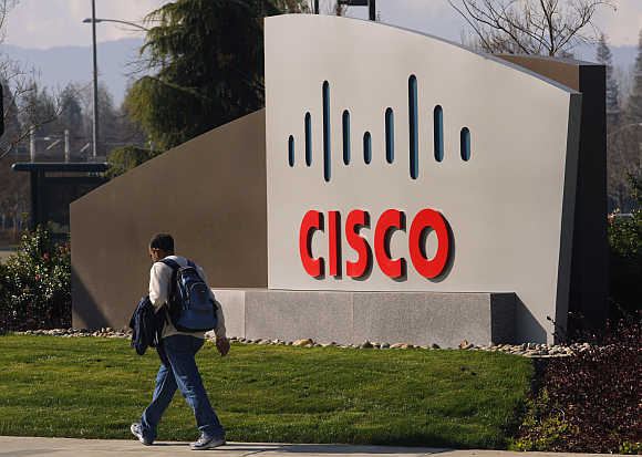 A pedestrian walks past the Cisco logo at the technology company's campus in San Jose, California.