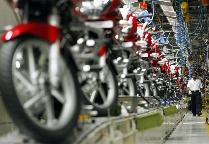 A worker walks beside newly built motorbikes at the Bajaj Auto Ltd. plant