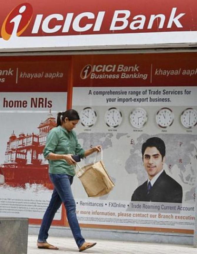 A woman walks past an ICICI Bank.