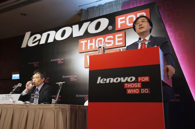 Lenovo Chairman and Chief Executive Officer Yang Yuanqing (R) speaks while attending a news conference on the company's annual results.