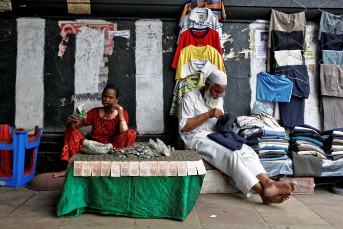 A woman exchanging damaged Indian currency waits for customers along a roadside in New Delhi.