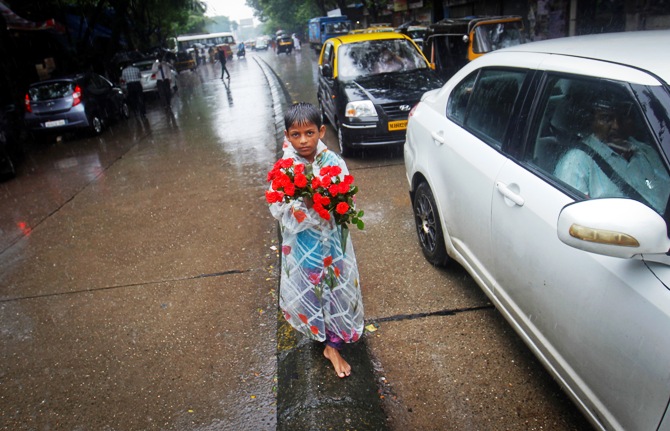 A boy sells roses while standing on a road divider during monsoon rains in Mumbai.