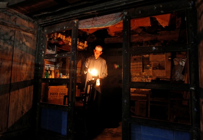 A barber lights candles after a power-cut due to curtailment, at his shop in Srinagar.