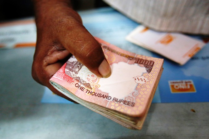 A customer hands a bundle of Indian Rupee currency notes to a teller at a financial institution in Mumbai.