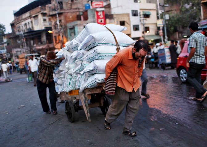 Labourers use a handcart to carry sacks at a wholesale grocery market in the old quarters of Delhi.