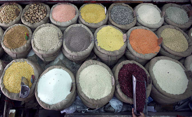 A retail trader scoops kidney beans at his shop in Jammu.