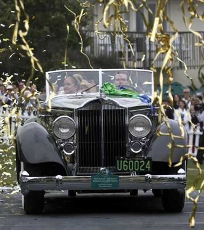 Confetti streams down as Joseph Cassini and his daughter Caroline Cassini drive on stage to receive the Best of Show award for their 1934 Packard 1108 Twelve Dietrich Convertible Victoria at the Concours d'Elegance on the 18th fairway of the Pebble Beach Golf Links in Pebble Beach, California.