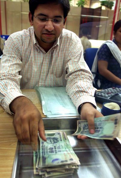 A worker counts Indian currency at a money changer.