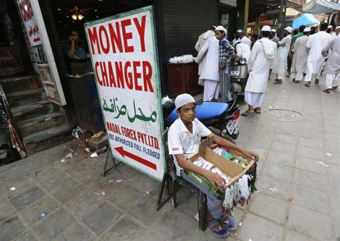 A boy sells prayer beads as he sits outside a currency exchange shop in New Delhi, August 21, 2013.