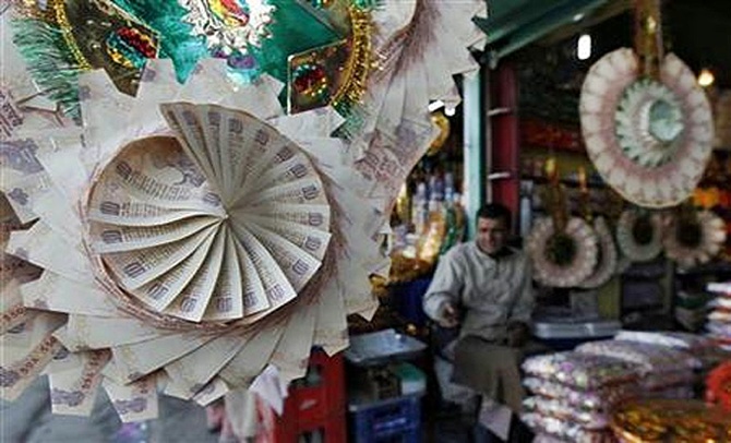 A Kashmiri shopkeeper sits near garlands made of currency notes at a market in Srinagar.