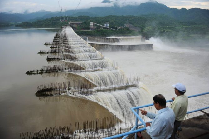 Indian officials look at the overflowing Sardar Sarovar Narmada dam.