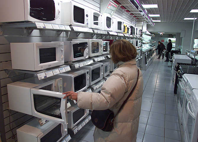 A customer looks at microwave ovens on display at a Paris retailer in France.