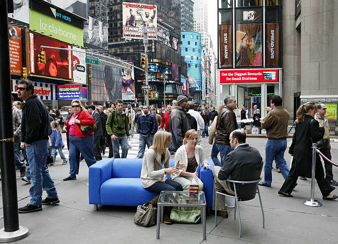 Two ladies sit and talk with the 'Good Listener' on the blue couch in New York City's Times Square. The couch will travel across the United States as Kleenex, the inventor of facial tissues, invites people to release their emotions.