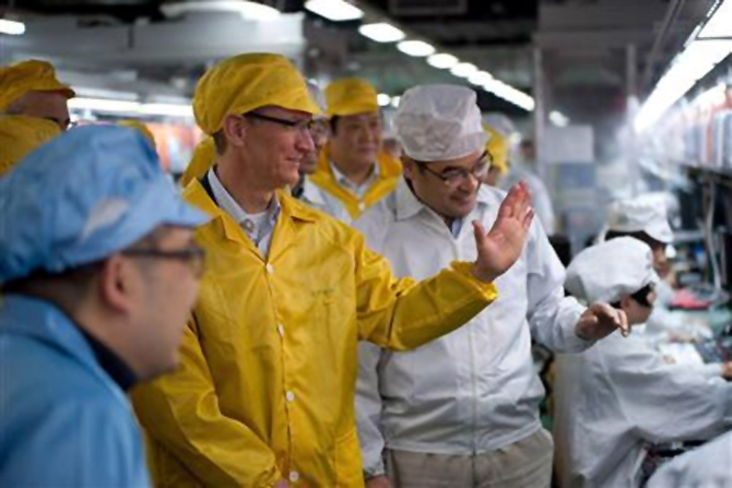 Apple Chief Executive Officer Tim Cook (2nd L) talks to employees as he visits the iPhone production line at the newly built Foxconn Zhengzhou Technology Park, Henan province.