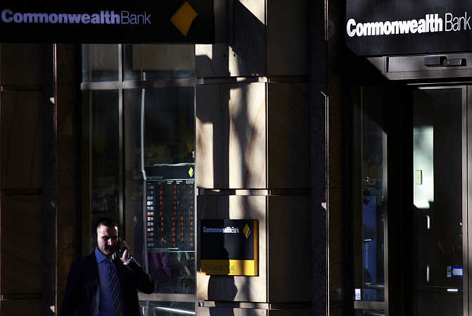 A man talks on his mobile phone as he walks past a Commonwealth Bank branch in central Sydney.