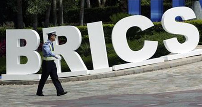 A traffic policeman walks past a signage decoration for BRICS Summit.