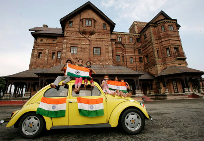 Children hold Indian national flags as they sit on a car during a photo-shoot in front of Hari Palace during the Independence Day celebrations in Jammu.