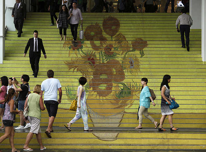 People walk on stairs featuring a five-metre-high reproduction of Vincent van Gogh's signature painting 'Sunflowers', at the entrance to Ocean Terminal in Hong Kong.