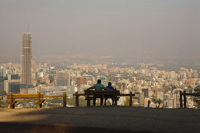 A man and his son enjoy the view of the Andes Mountains Range at the San Cristobal Hill in Santiago de Chile, Chile.