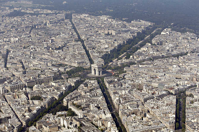 An aerial view shows the Arc de Triomphe, centre, at the centre of the Place Charles de Gaulle and rooftops of residential buildings in Paris, France.