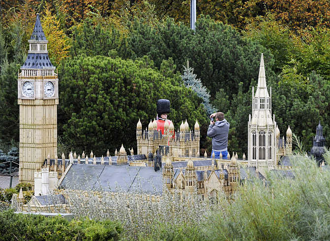 A tourist takes a picture of a model of an English guard in front of a miniature reproduction of the Buckingham Palace in the Mini-Europe park, where all the models are built at a scale of 1:25, in Brussels, Belgium.