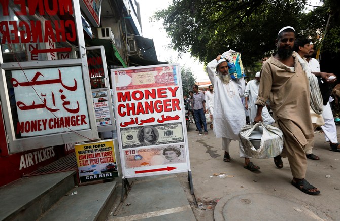 Men walk past a currency exchange shop in New Delhi.