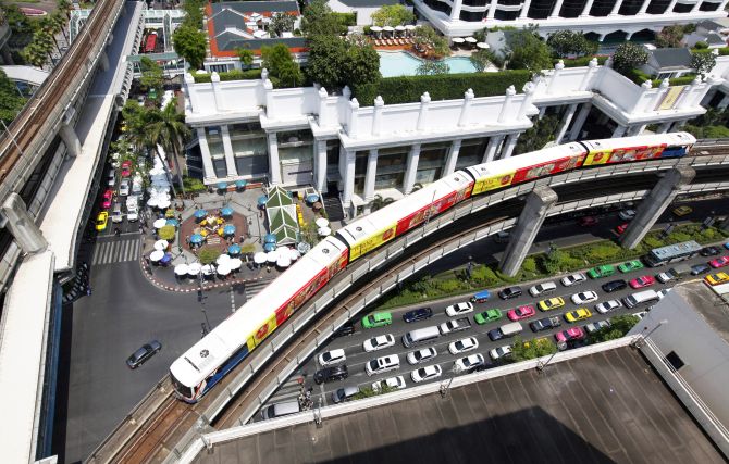 A skytrain passes over vehicles on the road in Bangkok.