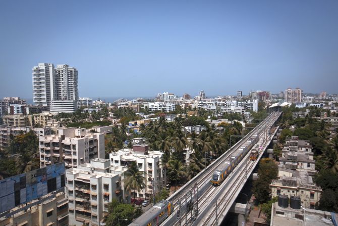 Metro trains pass through a residential area during its first official safety trial run in Mumbai.