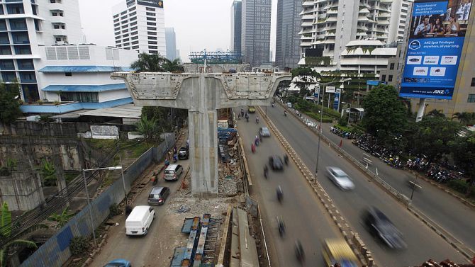 Vehicles drive past the construction site for a new highway in the business district in Jakarta.